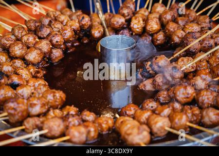 Aufgespiegelte Fleischbällchen, die kreisförmig um einen dampfenden Metalltopf angeordnet sind. Stockfoto
