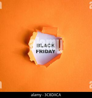 Schwarzer Freitag-Text auf weiß mit orangefarbenem Lochpapier. Stockfoto