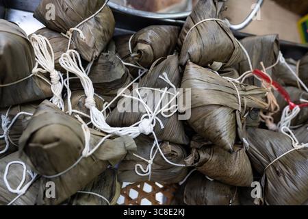 Bananenblätter umhüllte Pakete, bekannt als Khao Tom Mat, ein klebriger Reisknödel, ein beliebter Snack für Street Food in Bangkok, Thailand. Stockfoto
