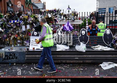 Mitarbeiter und Freiwillige des Stadtrates von Birmingham beginnen, die Blumen und Tribut zu entfernen, die Ozzy Osbourne an der Black Sabbath Bridge Bank in der Broad Street in Birmingham hinterlassen hat. Black Sabbath Frontmann Ozzy starb letzten Monat im Alter von 76 Jahren. Bilddatum: Montag, 4. August 2025. Stockfoto