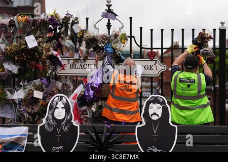 Mitarbeiter und Freiwillige des Stadtrates von Birmingham beginnen, die Blumen und Tribut zu entfernen, die Ozzy Osbourne an der Black Sabbath Bridge Bank in der Broad Street in Birmingham hinterlassen hat. Black Sabbath Frontmann Ozzy starb letzten Monat im Alter von 76 Jahren. Bilddatum: Montag, 4. August 2025. Stockfoto