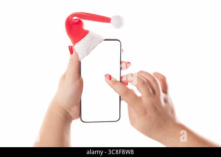 Weibliche Hände halten Handy mit weihnachtsmann Hut isoliert auf weißem Hintergrund. Leerer weißer Bildschirm. Konzept der Weihnachtsgratulierung. Stockfoto