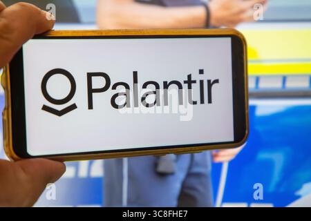 Palantir symbolisches Bild: PALANTIR-Logo auf einem Smartphone mit einem Polizisten im Hintergrund Stockfoto
