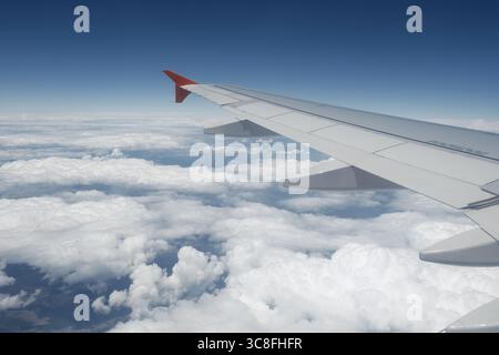 Ein ruhiger Blick auf einen Flugzeugflügel über dramatischen Wolken und Himmel, aufgenommen von einem Passagiersitz während des Fluges. Stockfoto