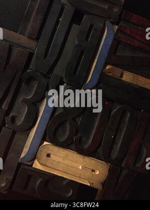 Nahaufnahme verschiedener Vintage-Holzdruckblöcke mit Letterpress-Zeichen, die ein abstraktes Muster bilden und an traditionelle Drucktechniken erinnern Stockfoto