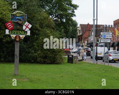 Schild für Epping in Essex, Großbritannien, mit dem Stadtwappen im Vordergrund und der Epping High Street auf der rechten Seite. Traditionelle Stadtbeschilderung am Eingang zu dieser historischen englischen Marktstadt. Stockfoto