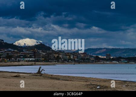 Malerischer Blick auf die Adriaküste mit dem schneebedeckten Gran Sasso d'Italia im Hintergrund, der einen beeindruckenden Kontrast schafft Stockfoto