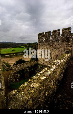 Blick von der Spitze der Mauer auf die Ruinen von Chepstow Castle in Wales, vor einem grauen stürmischen Himmel Stockfoto