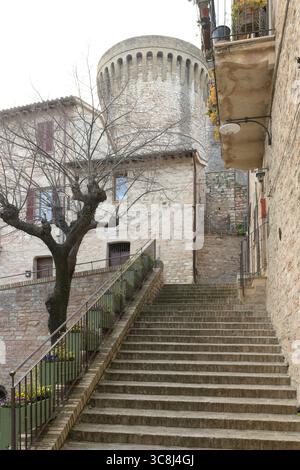 Eine Steintreppe führt zu einem mittelalterlichen Turm in der historischen Stadt Spello, Umbrien, Italien, umgeben von traditionellen Häusern und engen Gassen. Stockfoto