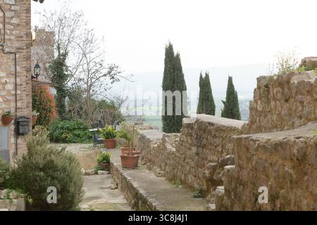Alte römische Stadtmauern von Spello (Hispellum), Umbrien, Italien, mit mittelalterlichen Anbauten und dem Glockenturm von Santa Maria Maggiore im Hintergrund. Stockfoto