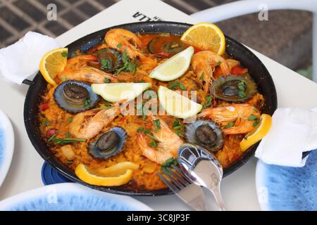 Paella mit Meeresfrüchten und lapas (Limetten) und Zitrone, traditionelles kanarisches Gericht, das auf Lanzarote, den Kanarischen Inseln, Spanien serviert wird. Stockfoto