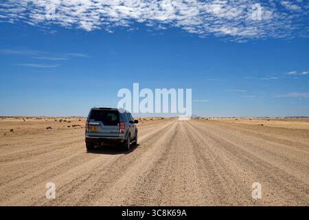 Namib: Allradfahrzeug auf Schotterstraße D1918), Wüste westlich von Spitzkoppe (im Hintergrund), Erongo Region, Namibia Stockfoto