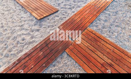 Holzstege an einem Sandstrand, geometrisches Muster und warme, natürliche Texturen, ideal für Reisen, Sommer, Natur und Abenteuer Stockfoto