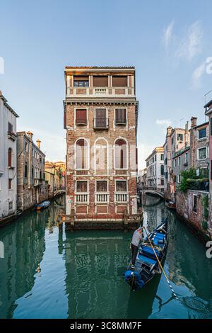 Gondelfahrt vor dem Palazzo Tetta durch einen schmalen venezianischen Kanal gesäumt von farbenfrohen historischen Gebäuden, Venedig, Italien. Stockfoto