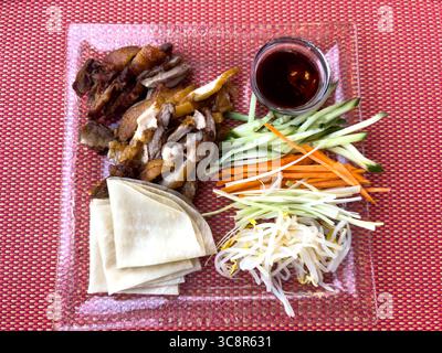 Chinesische Küche mit Peking-Ente und Pfannkuchen mit gehackter Gurke, Karotten, Sojasprossen und einem Dip mit Hoisin-Sauce Stockfoto