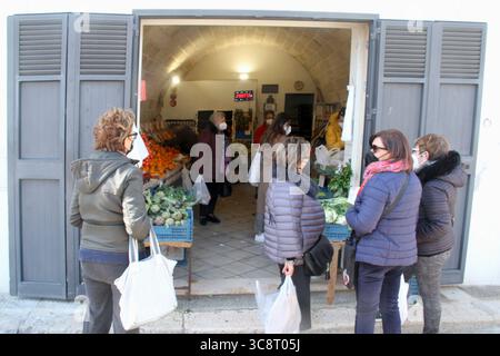 Polignano a Mare, Italien. Gruppe von Käufern, die während der COVID-19-Pandemie Masken vor einem Lebensmittelgeschäft trugen. Stockfoto