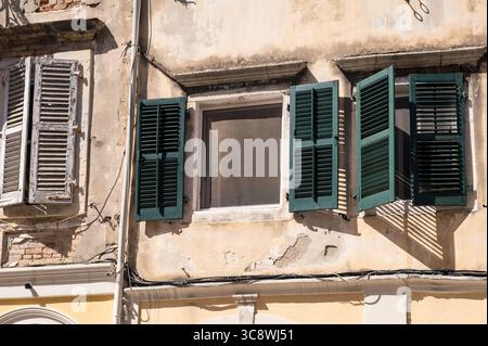 Alte mediterrane Mauer mit Holzläden und abblätterndem Gips in Korfu, Griechenland Stockfoto