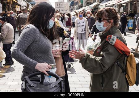 24. Februar 2021, Jerusalem, Israel: Ein IDF-Oberst überredet Käufer zur Impfung gegen COVID-19. Das IDF-Heimatfrontkommando in Abstimmung mit Magen David Adom, der als israelische Organisation des Roten Kreuzes und als führendes EMS fungiert, macht die COVID-19-Impfung für diejenigen zugänglich, die noch immer eine mobile Impfstation aus einer Wohnwagenkarawane auf dem Shuk Mahane Yehuda-Markt von Jerusalemâ betreiben oder ablehnen. (Bild: © Nir Alon/ZUMA Wire) Stockfoto