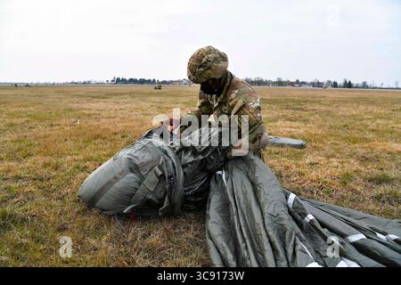 18. Februar 2021 - Udine, Italien - Ein Fallschirmjäger der US-Armee, der dem 1. Bataillon, 503. Infanterieregiment, 173. Luftlandebrigade, zugeteilt ist, sichert seine Ausrüstung nach einer Luftlandeoperation des 86. Luftwagens C-130 Hercules während der Übung Eagle Ace II auf der italienischen Luftwaffenbasis Rivolto, Udine Italien, Udine Italien, am 18. Februar 2021 unter COVID-19-Präventionsbedingungen. Ziel dieser Operation ist es, die Beziehungen zum Gastland zu verbessern, das Bündnis zu stärken und die Interoperabilität der NATO zu erhöhen. Die 173. Luftlandebrigade ist die US-Armee-Notfalltruppe in Europa. Stockfoto