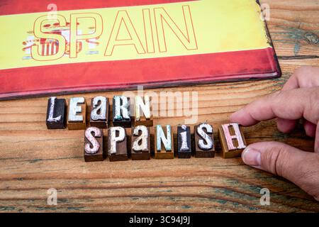 Lerne spanische Botschaft mit Holzbuchstaben und Hintergrund der spanischen Flagge. Stockfoto