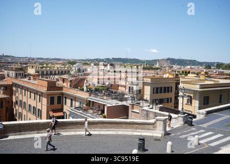 Rom, Italien, 13. Juli 2025: Panoramablick auf Terrakotta-Dächer und historische Gebäude im römischen Stadtbild, genießen die Menschen auf einer Terrasse. Stockfoto