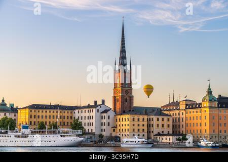 Blick auf den Turm der Riddarholmen-Kirche, der die Skyline zwischen historischen Gebäuden und einem schwimmenden Heißluftballon durchquert, Stockholm, Schweden. Stockfoto