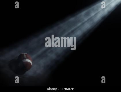 Ein american Football-Sportball, der von einem einzigen ätherischen Licht auf einem dunkelschwarzen Hintergrund beleuchtet wird – 3D-Rendering Stockfoto