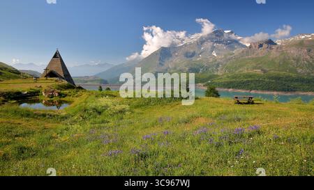 Eine moderne pyramidenförmige Kirche am Ufer des Lac du Mont Cenis (See Mont Cenis) in Savoie, Frankreich, mit dem Mount Giusalet im Hintergrund Stockfoto