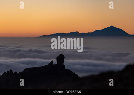 Blick auf einen stilisierten felsigen Gipfel inmitten eines Wolkenmeers mit fernen Bergen unter einem weichen Gefälle, Pico de las Nieves, Kanarische Inseln, Spanien. Stockfoto