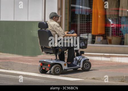 Ronda, malaga, spanien 20. juni 2022 Mann mit eingeschränkter Mobilität im elektrischen Rollstuhl, der die Straße überquert Stockfoto
