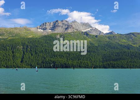 Windsurfen und Wingsurfen auf dem Alpensee Silvaplana an einem sonnigen Sommertag mit Berg in Silvaplana, Maloja, Graubünden, Schweiz Stockfoto