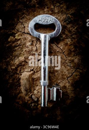 Eine Nahaufnahme eines silbernen Schlüssels mit der Aufschrift „M32H“ auf einer strukturierten, braunen Oberfläche. Stockfoto