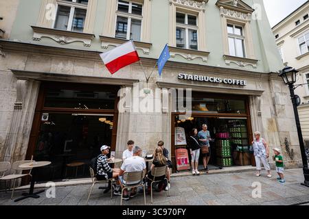Krakau, Polen - 08. Juli 2025: Starbucks Coffee Shop mit Sitzplätzen im Freien in Krakau, wo Leute Kaffee genießen. Stockfoto