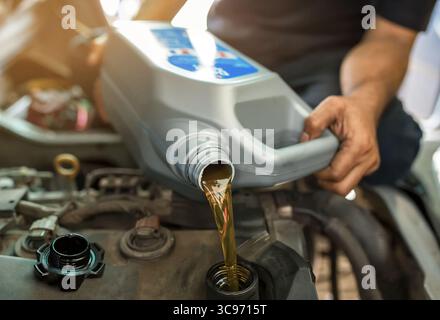 Kfz-Mechaniker ersetzen und gießen frisches Öl in den Motor an der Wartungsreparaturstation. Stockfoto
