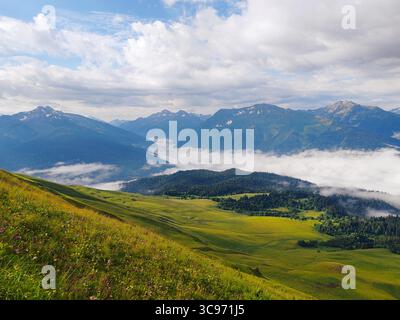 Wunderschöne Berglandschaft mit lebhaften grünen Hügeln, nebeligen Tälern und dramatischen Wolken, die eine ruhige Atmosphäre schaffen Stockfoto