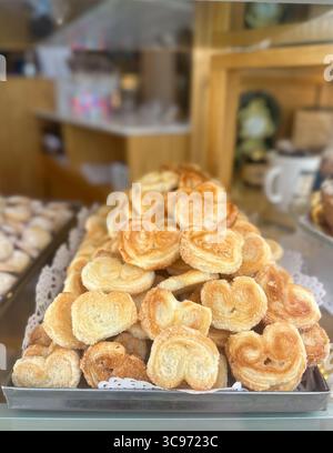 Eine detaillierte Nahaufnahme von herzförmigen Palmiers (auch bekannt als Elefantenohren oder französische Herzen). Der Hintergrund ist verschwommen, was auf eine Bäckerei hindeutet Stockfoto