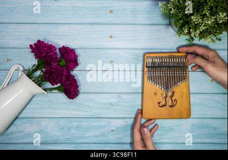 Blick von oben auf die Hand eines Mädchens Spiel ein afrikanisches hölzernes Instrument Kalimba oder Mmbira ist ein afrikanisches Musikinstrument auf Vintage-blauem hölzernen Tisch Textur Backgr Stockfoto