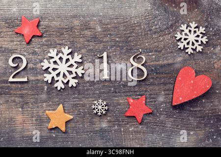 Glückliches neues Jahr 2018 mit echten Holzfiguren mit Schneeflocken und Sternen auf hölzernem Hintergrund mit Schnee. Stockfoto