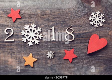 Happy New Year 2018 mit echten Holzfiguren mit Schneeflocken und Sternen auf hölzernem Hintergrund Stockfoto
