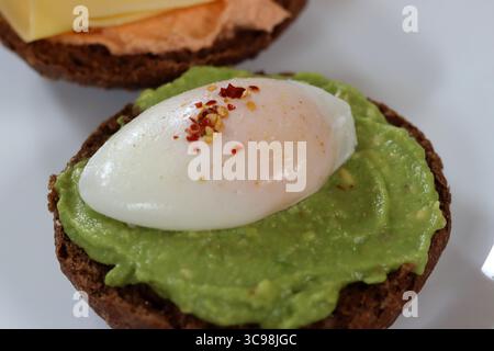 Avocadotoast mit pochiertem Ei auf einem weißen Teller, Nahaufnahme Stockfoto