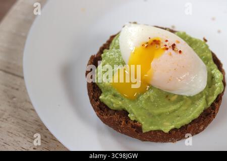 Avocadotoast mit pochiertem Ei auf einem weißen Teller, Nahaufnahme Stockfoto