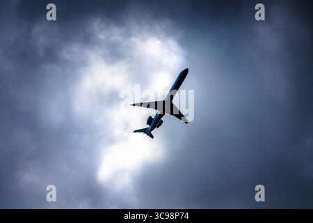 Flugzeug im Flug auf bewölktem Tagesblick von unten, Luftverkehr Stockfoto