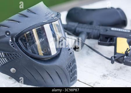 Paintball-Munition. Schwarzer Helm und Pistole draußen. Nahaufnahme des Bildes. Stockfoto