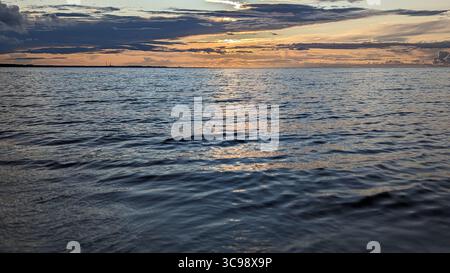 Ozean Horizont bei Sonnenuntergang mit sanften Wellen und goldenen Reflektionen, die sich durch friedlichen Meerblick erstrecken Stockfoto