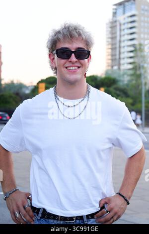 Porträt eines jungen kaukasischen Mannes, der lächelnd in die Kamera schaut, in der Stadtstraße steht. Stockfoto