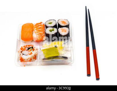 Buntes rohes Sushi in der Plastikbox zum Mitnehmen und Stäbchen isoliert auf weiß Stockfoto