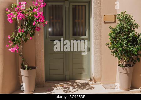 Blumen in Töpfen in der Nähe einer schönen grünen Tür, mediterrane Gemütlichkeit der Altstadt von Rethymno Stockfoto
