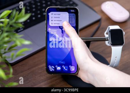 Poznan, Polen – 29. Juli 2025: Mobile iOS 26-Plattform auf einem iPhone, wobei die Hand eines Benutzers interagiert, um Widgets und Liquid Glass-Anwendung anzupassen Stockfoto