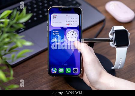 Poznan, Polen – 29. Juli 2025: Eine Hand interagiert mit den intuitiven ios 26 Liquid Glass Widgets des iPhones und hebt die Integration moderner Smart-Geräte hervor Stockfoto