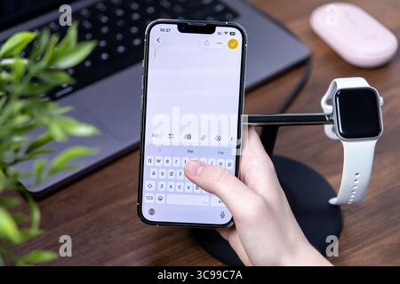 Posen, Polen – 29. Juli 2025: Eine Hand interagiert mit einem Smartphone und zeigt das auf seiner modernen Tastatur, die aus fortschrittlichem ios 26 und Liquid Glass besteht Stockfoto